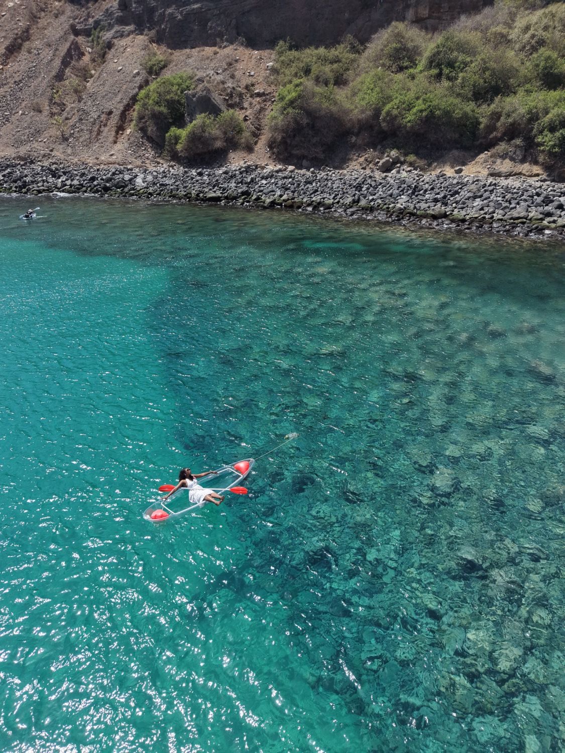 Kayak transparent sur l’eau turquoise au pied des falaises de Ouakam